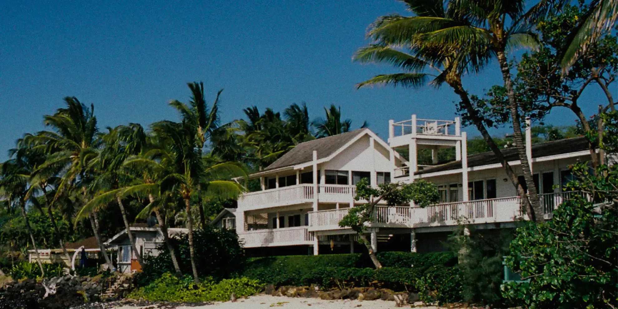 a beachfront white house surrounded by coconut trees 1980x992 1